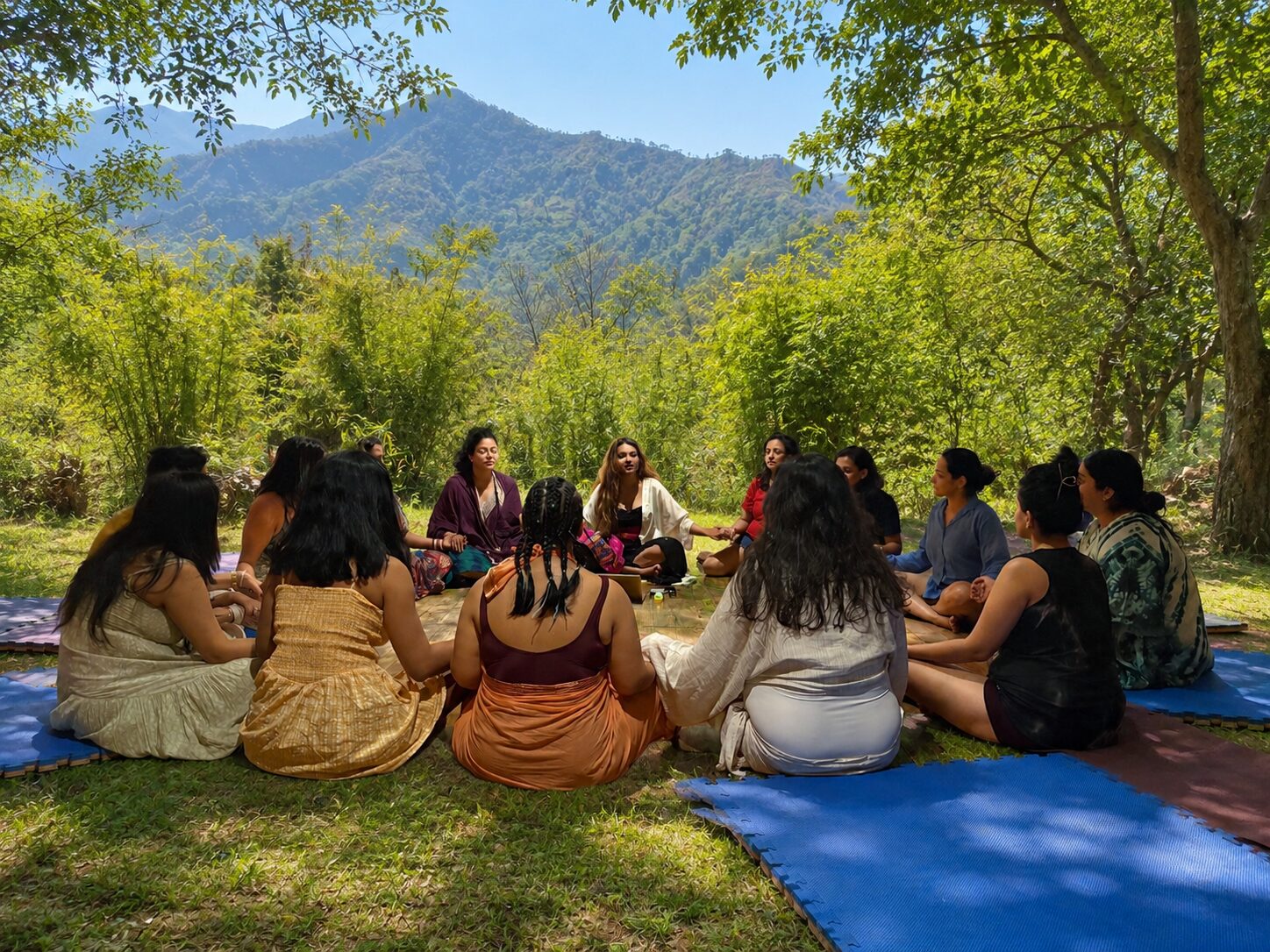 A circle of women sharing under trees with mountain views