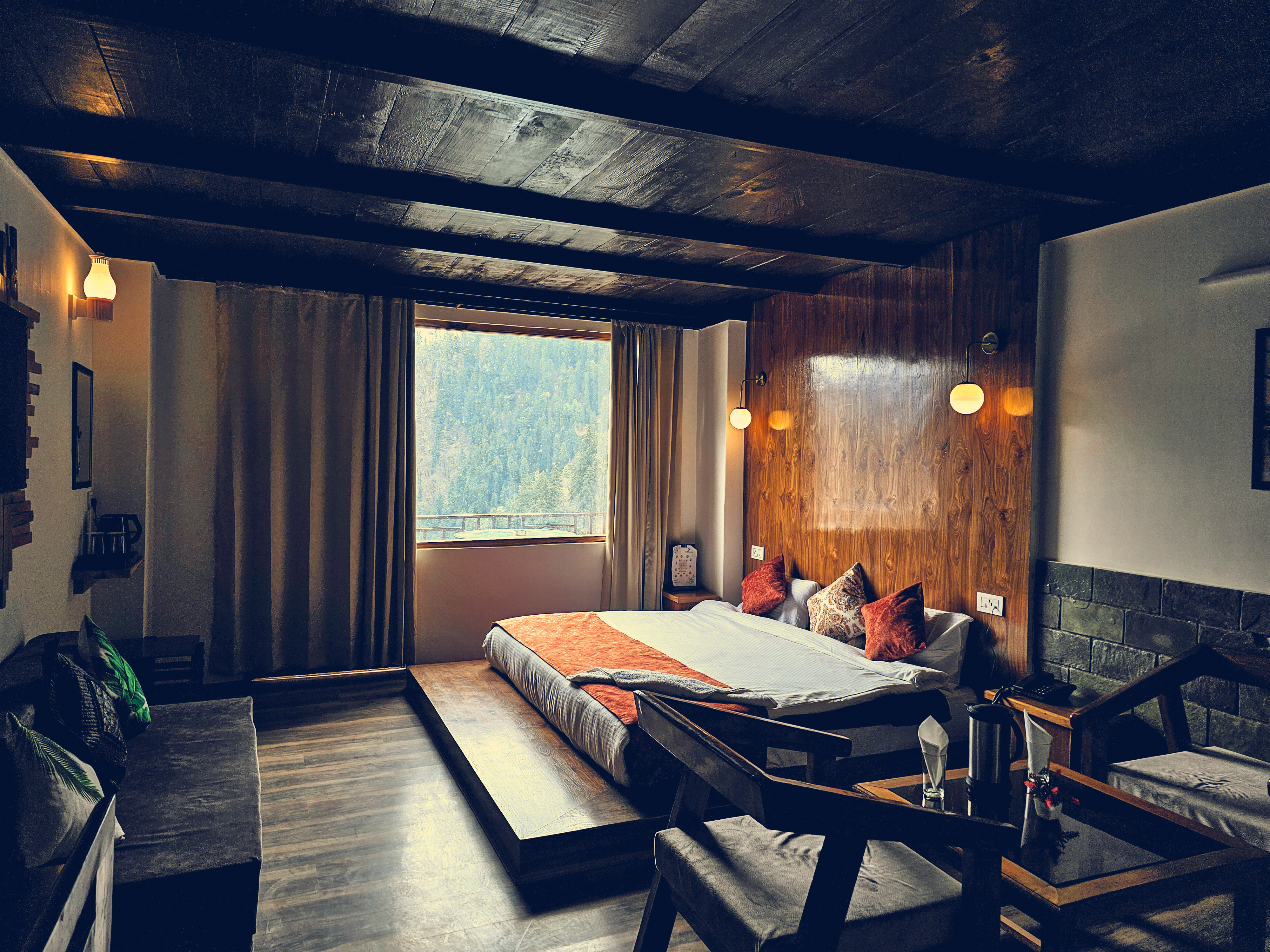 Family Suite with dark wooden beams and a picture window opening onto the Tirthan valley